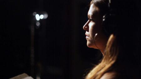 Side profile of a woman in a dark room with headphones on.
