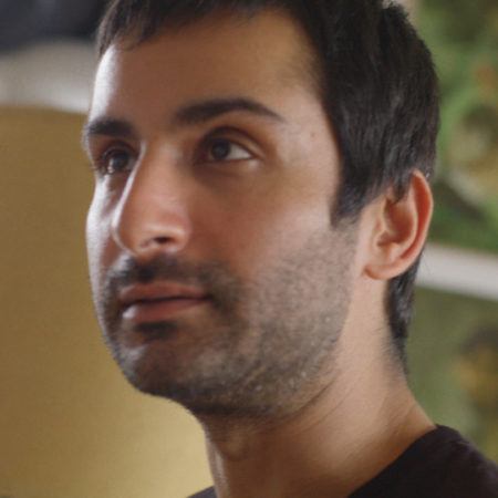 Three quarter portrait of Salman Toor looking off in the distance.