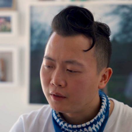 Tommy Kha eyes downcast, wearing a blue and white bandana around his neck.