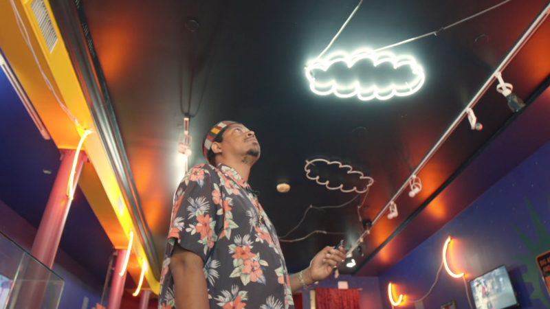 Azikiwe looking up at the ceiling of a neon cloud.