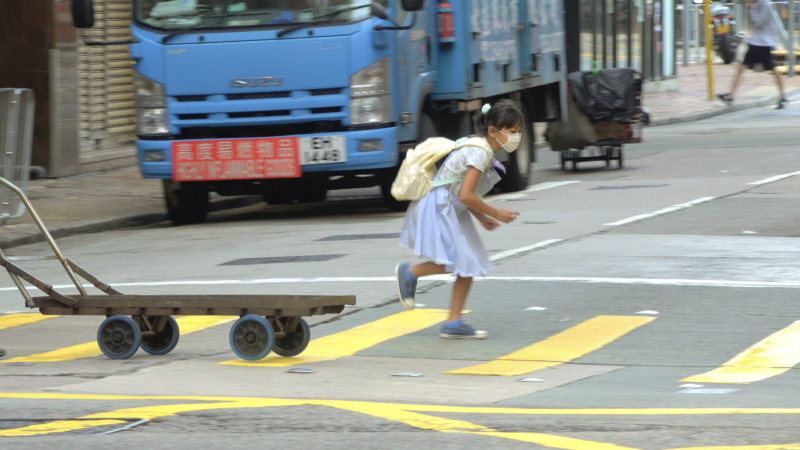 A child wearing a yellow backpack running across a yellow crosswalk.