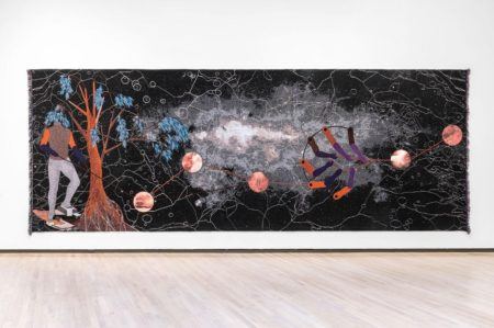Otobong Nkanga's long black tapestry "Double Plot," a headless figure and tree stand to the left while orbs float in the middle.