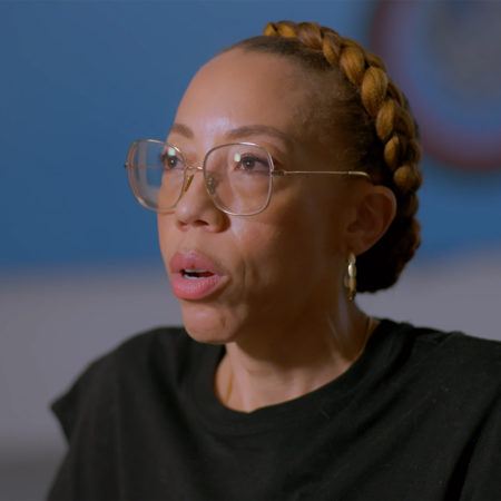 Amy Sherald wearing large framed glasses with her mouth slightly open in speech.