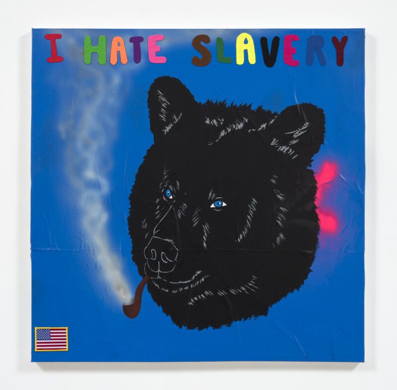 Blue background, above a black bear head smoking a pipe with smoke coming out of it and the colorful words, "I HATE SLAVERY." There's a small American flag patch in the bottom left corner.