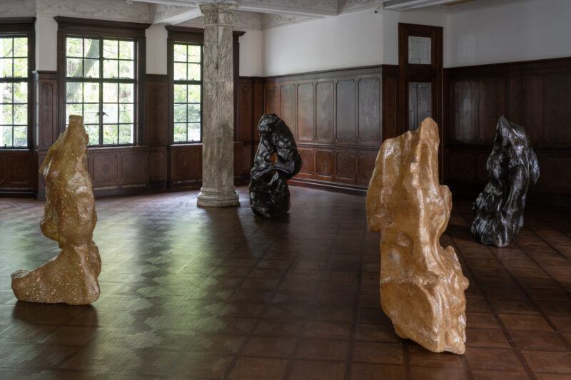 Four sculptures resembling stones are spread throughout a room