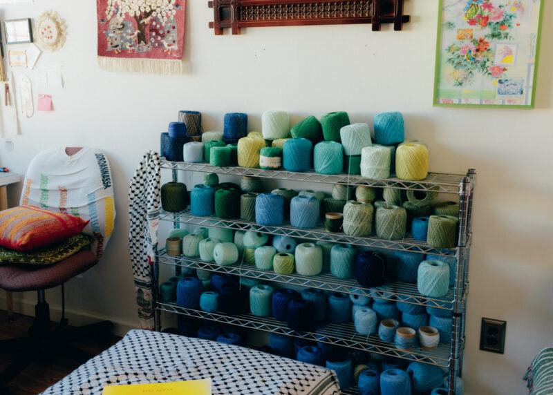 Shelf of spools of thread in a range of different shades of green and blue.