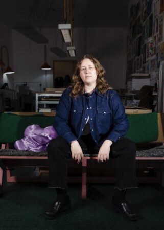 Johanna Maierski sitting on a bench in her darkly lit studio.