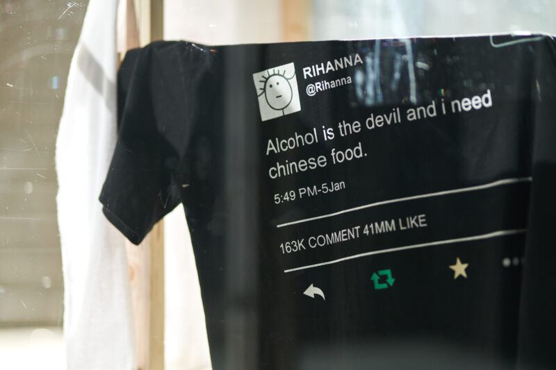 Black t-shirt with a Rihanna tweet printed on it that reads: "Alcohol is the devil and i need chinese food."