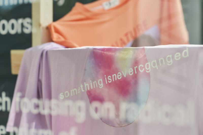 Close up of a pink t-shirt with white text that reads: "something isnevercgqnged"
