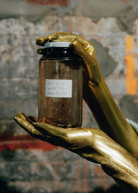 Gold gloved hands holding a jar.