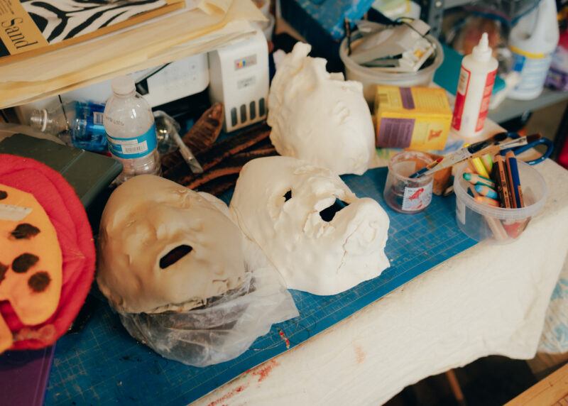 A table in the studio with unpainted face masks sitting on it.