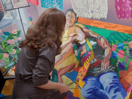 Aliza Nisenbaum working on a colorful, large-scale painting with intricate details and vibrant hues.