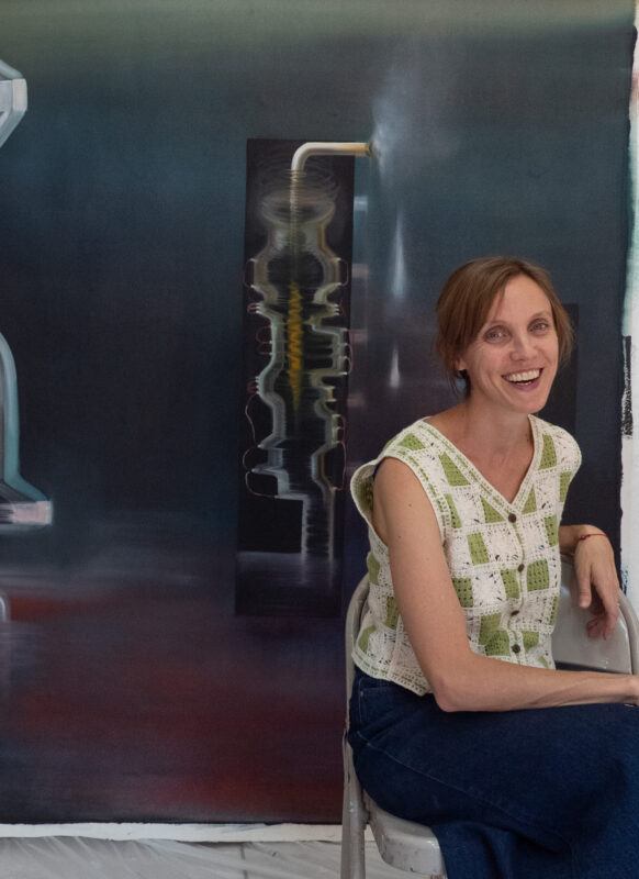 Carolina Fusilier sitting on a chair in front of a large painting hanging on a wall.