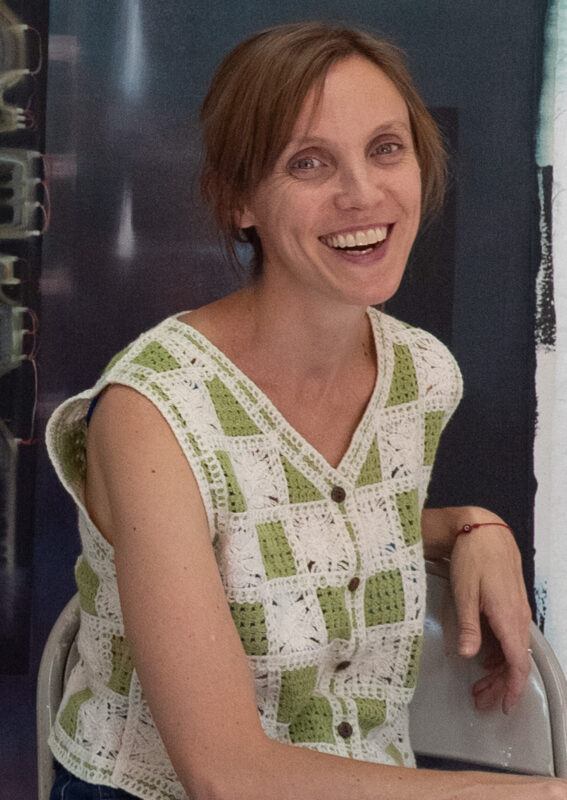 Carolina Fusilier sitting on a chair in front of a large painting hanging on a wall.