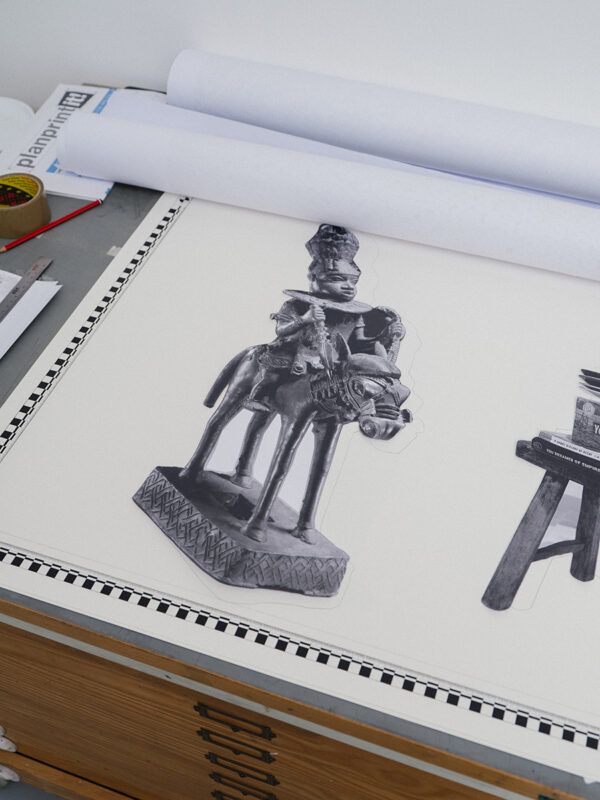 Black and white cut-out of a statue of a person on a horse placed pasted on white paper, sitting on a desk with art supplies.