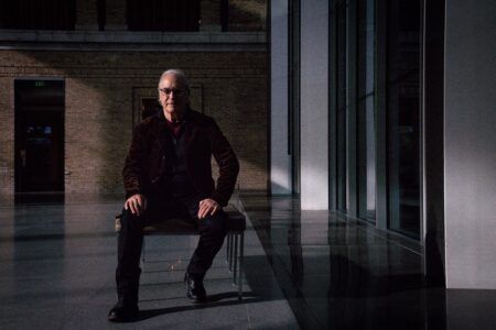 Alan Michelson sitting on a bench in a dimly lit marble and brick space.