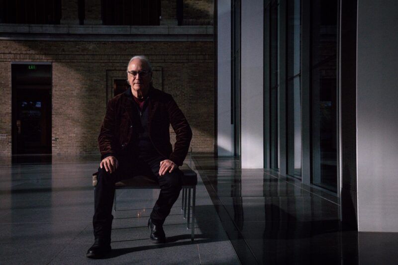 Alan Michelson sitting on a bench in a dimly lit marble and brick space.