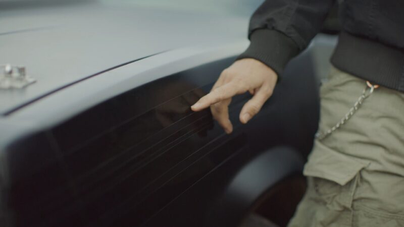 Hand pointing to a glossy striped designed on a matte black car.